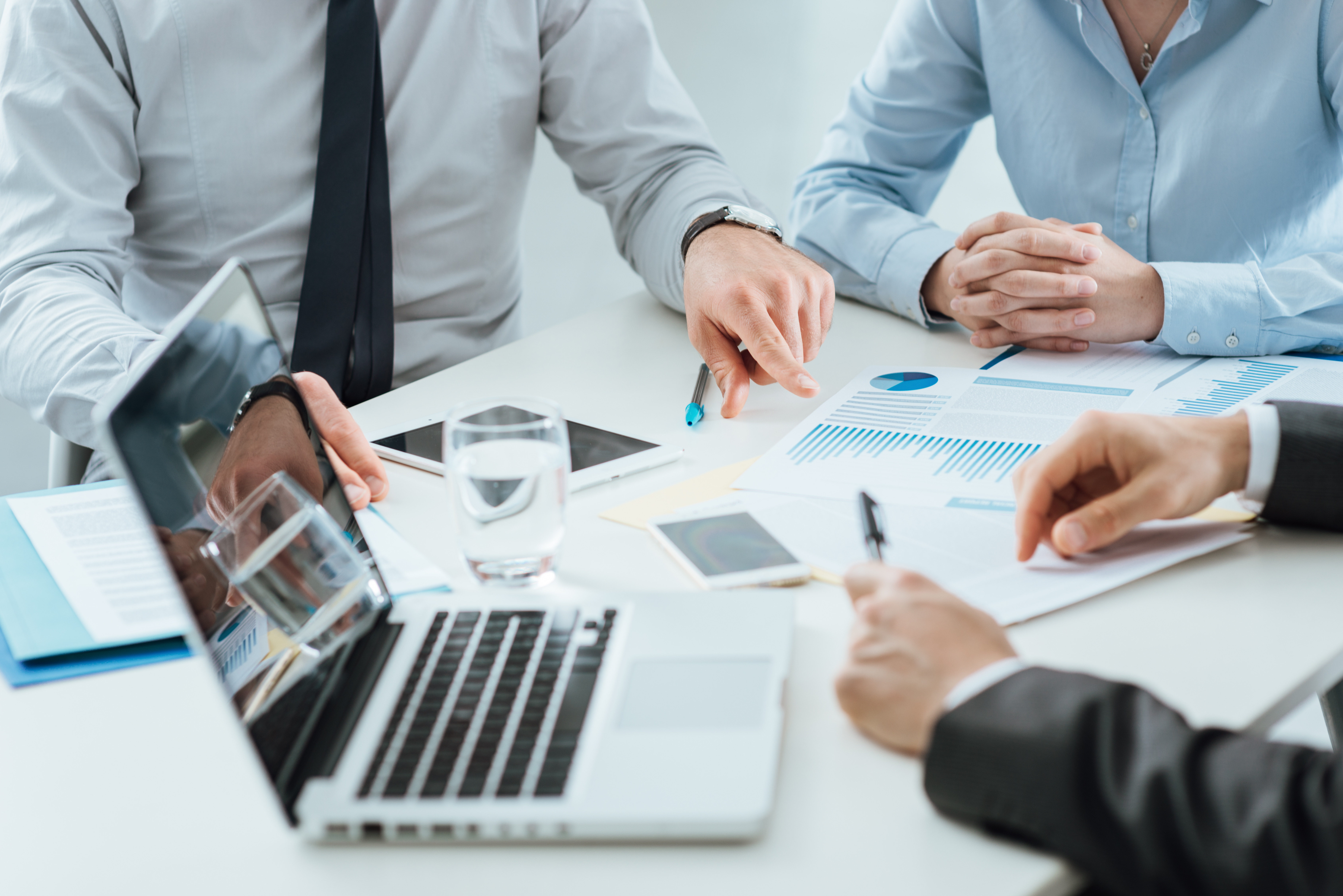 business people sitting around a table with paperwork and laptops