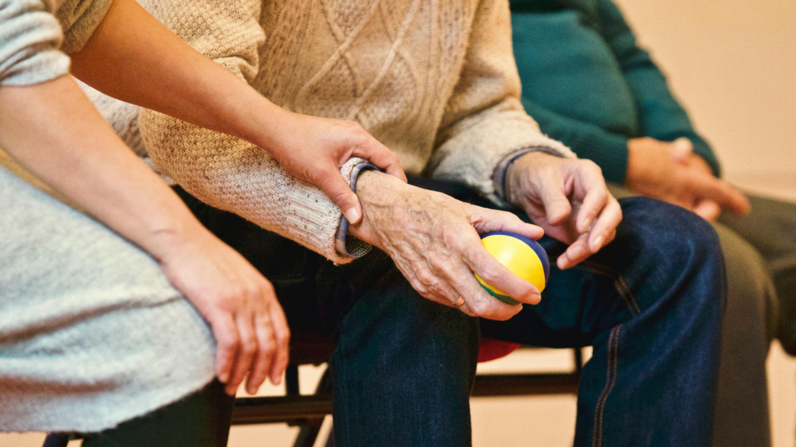 a carer holding the hands of an elderly person