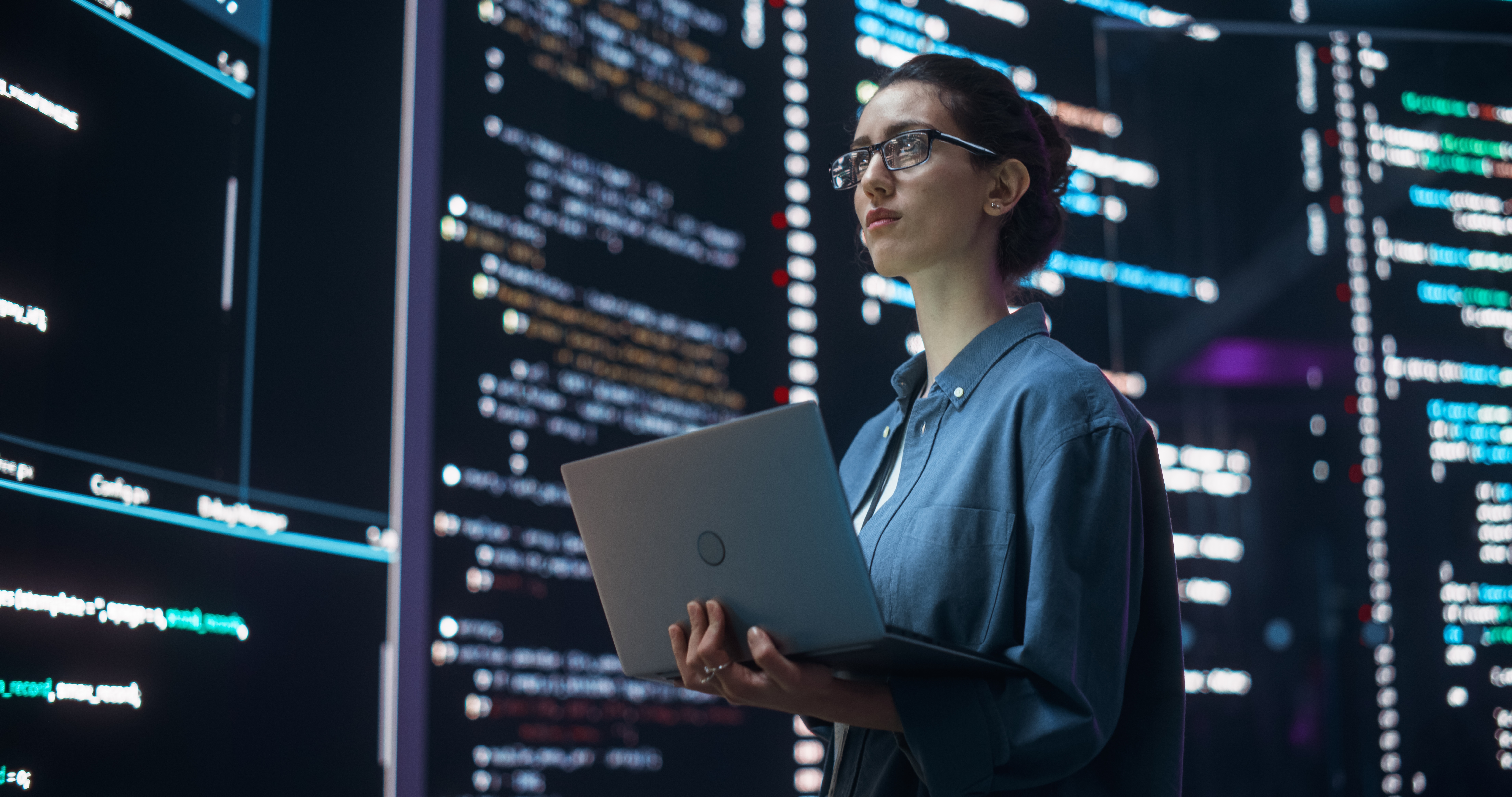woman holding a laptop with a screen full of code written around her