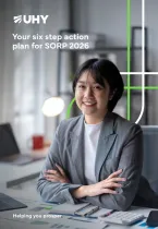 Smiling professional in a gray suit sits confidently at a desk with documents and calculator. Text reads "Your six step action plan for SORP 2026."