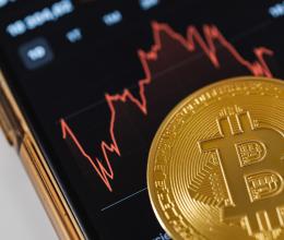 Close-up of a Bitcoin Coin Lying on a Screen Displaying a Stock Market Chart