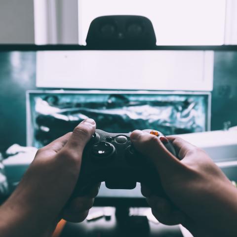 person holding game controller in front of television