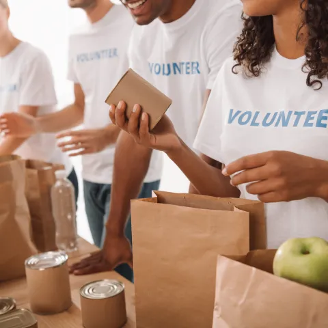 cropped shot of young volunteers group packing food and drinks for charity