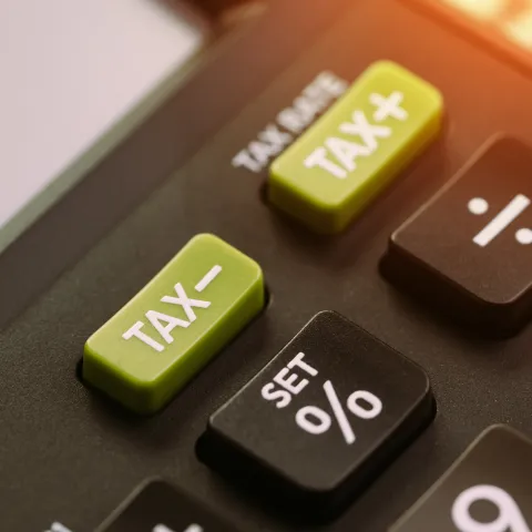 a close up shot of a calculator, focusing on the Tax+ and Tax- buttons