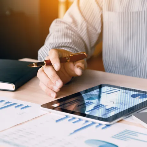 Businessman looking graph and summary report on digital tablet screen with analysis data result.