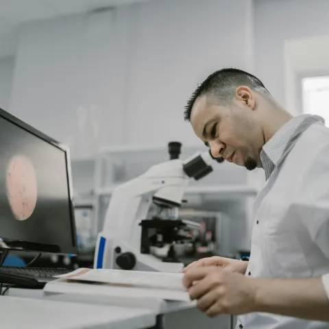 Man Sitting and Reading a Book on a Table Inside a Laboratory