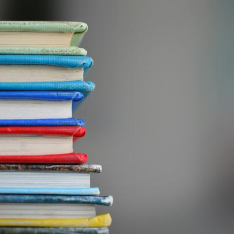 A stack of colourful books shot from a close up angle, with a blurred background.